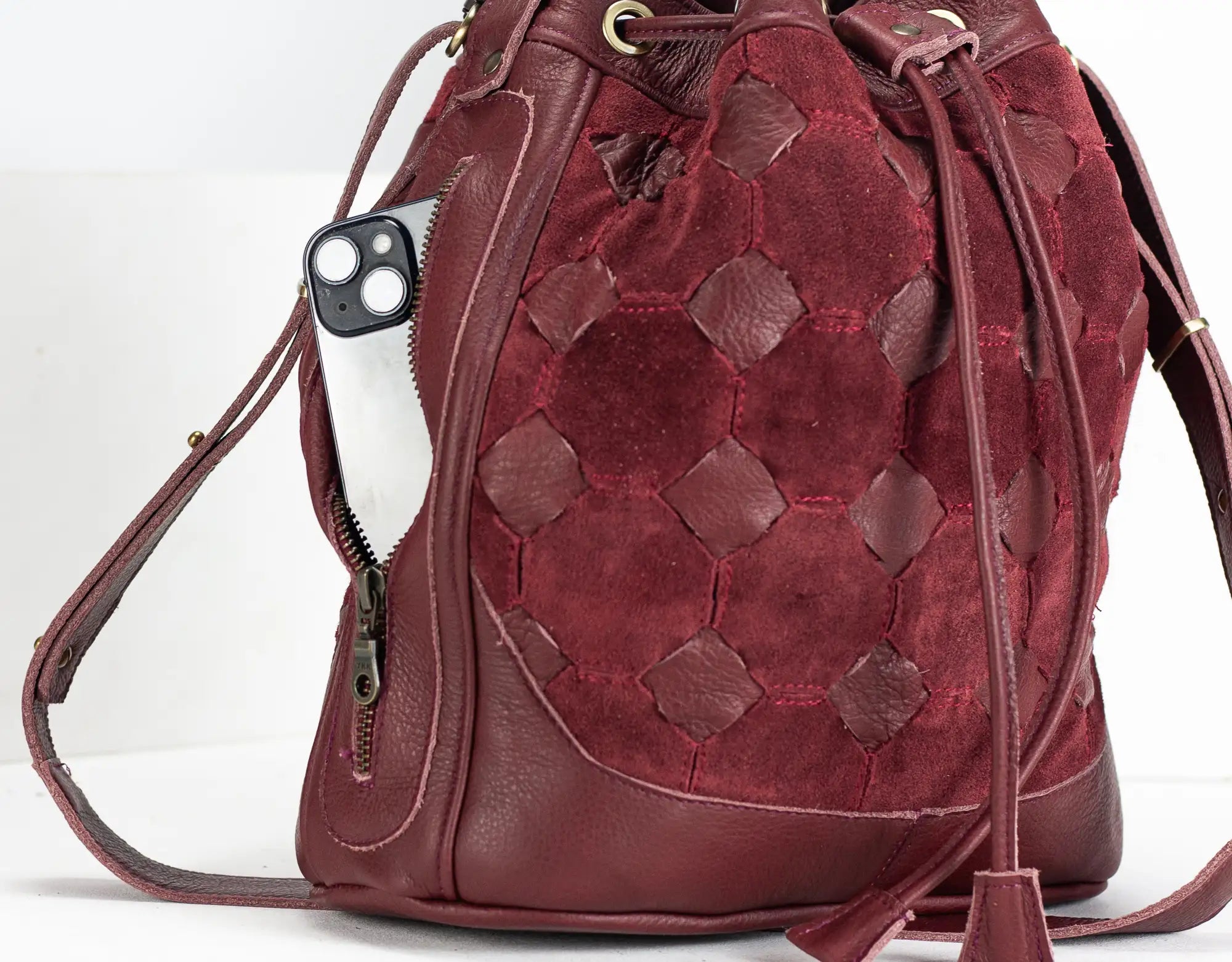 Red leather drawstring bag with geometric pattern on a white background