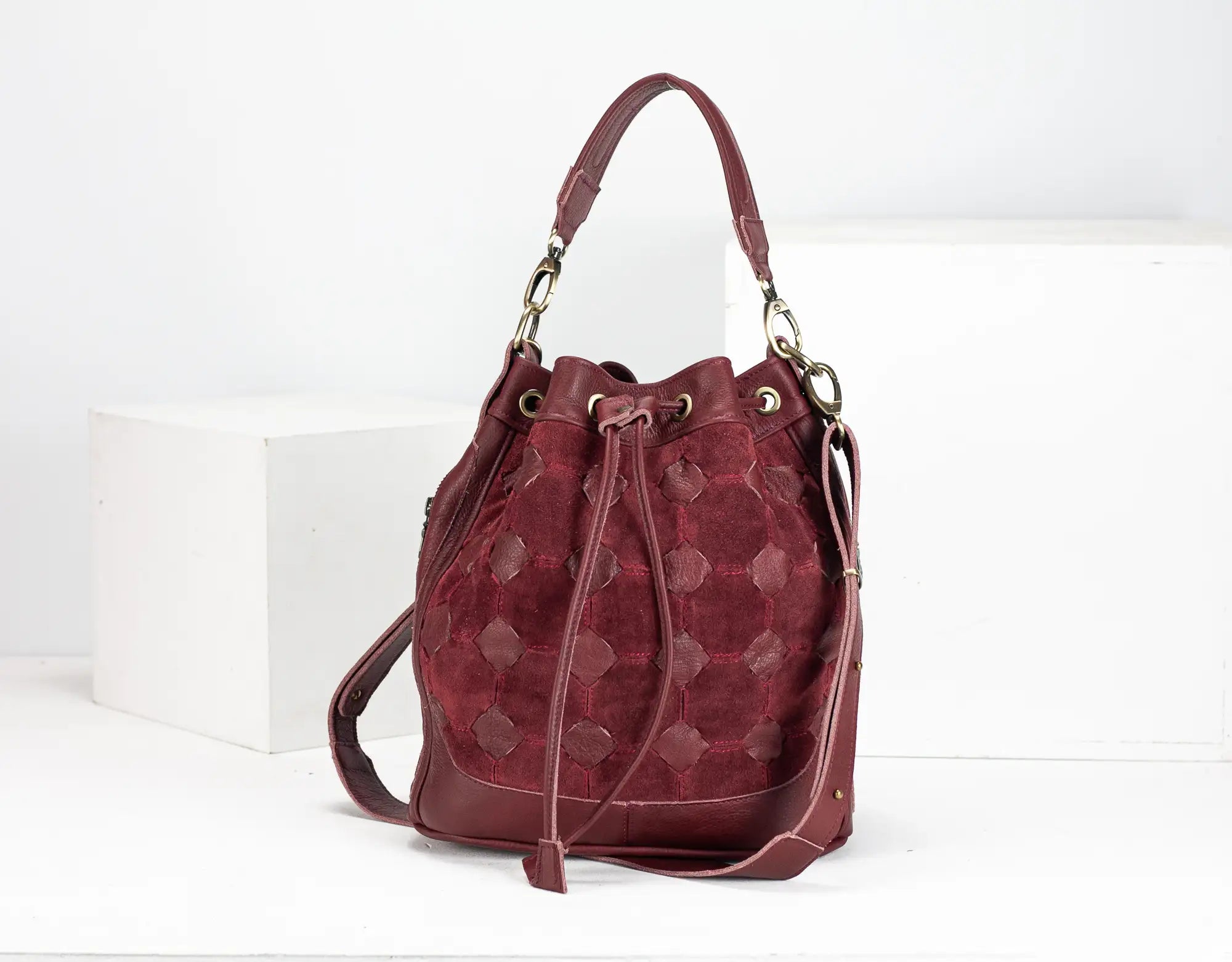 Maroon handbag with gold accents on a white background