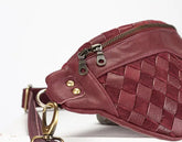 Maroon woven leather bag with gold zipper and hardware on a white background