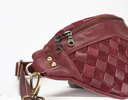 Maroon woven leather bag with gold zipper and hardware on a white background