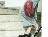 Person wearing black flats and a red woven bag on stone steps