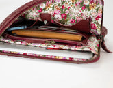 Floral-patterned clutch bag with a laptop inside on a white background