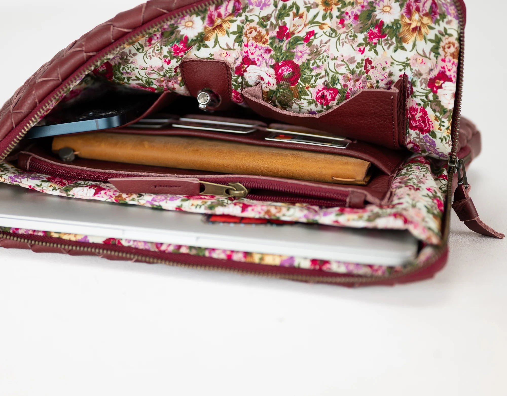 Floral-patterned clutch bag with a laptop inside on a white background
