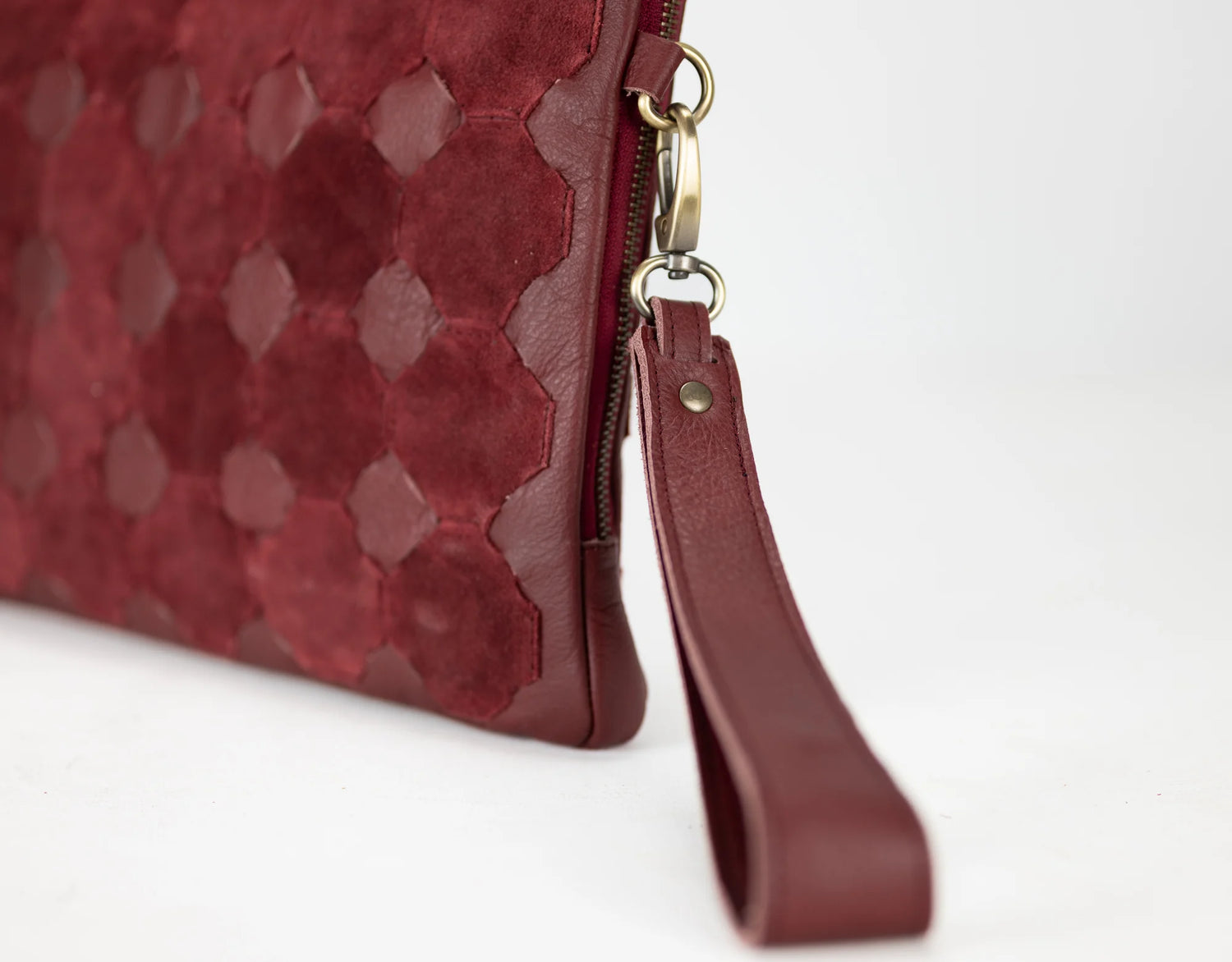 Close-up of a red textured clutch bag with a strap on a white background
