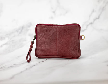 Red leather pouch with a strap on a marble background