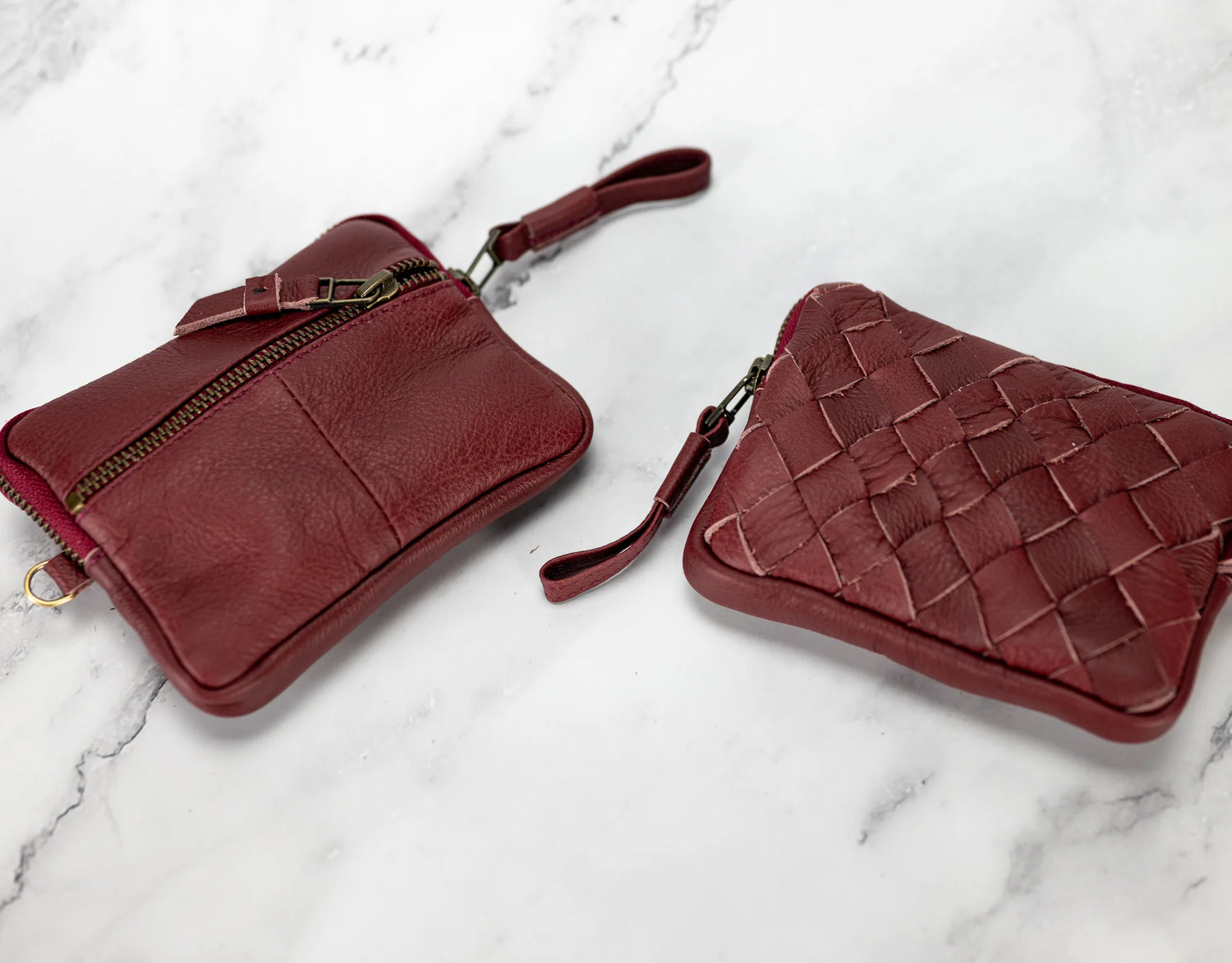 Two red leather bags on a marble surface