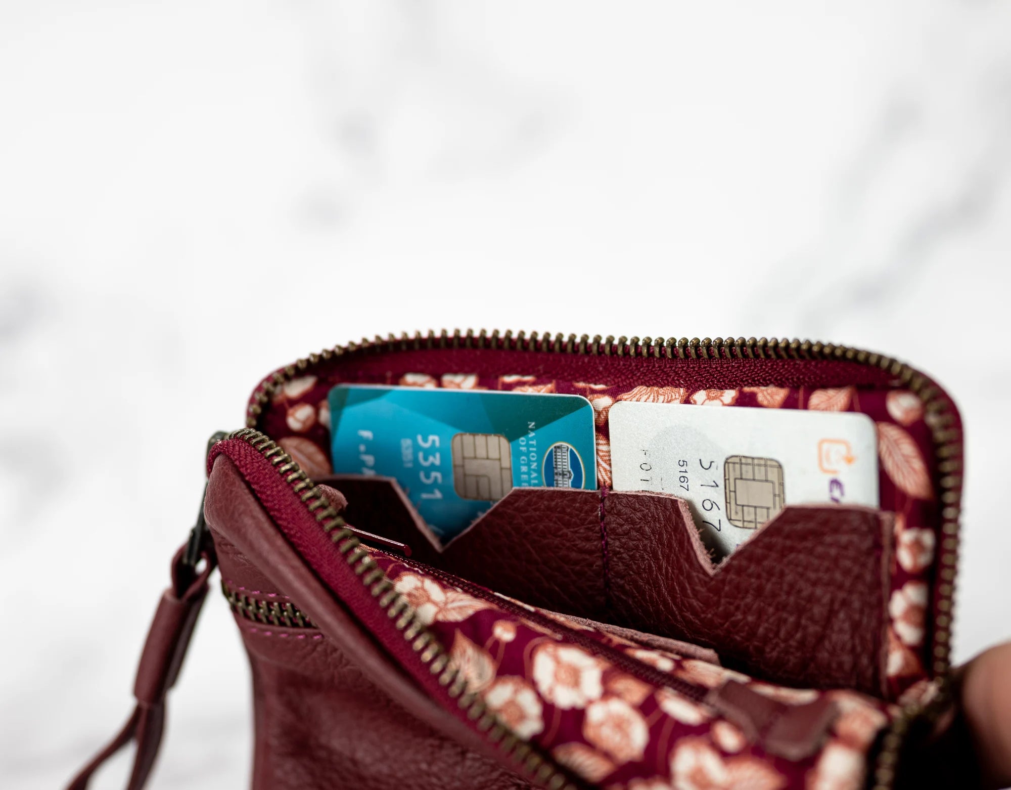 Open wallet with floral pattern showing two credit cards on a light gray background