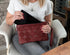 Woman sitting in a chair holding a red clutch bag with a brick wall background