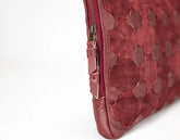 Close-up of a red textured clutch bag with a zipper on a white background