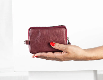 Hand holding a maroon leather wallet against a white background