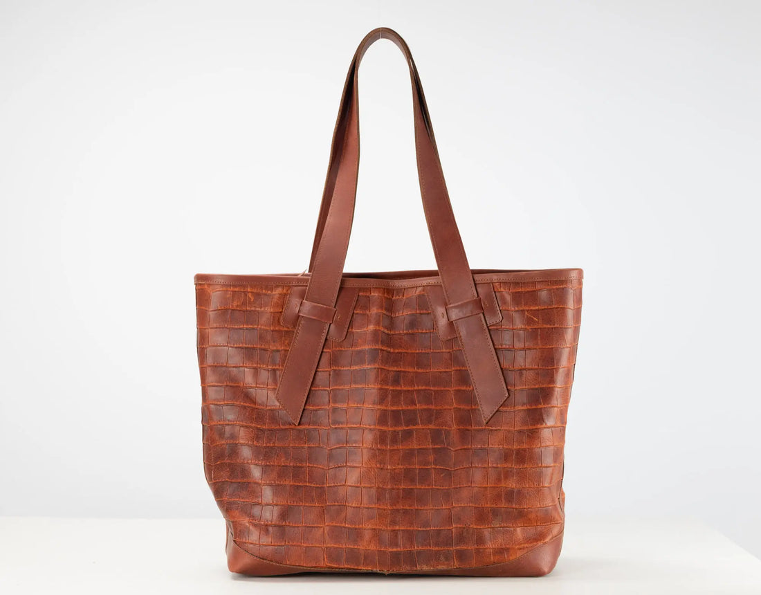 A brown crocodile-embossed leather tote bag with two shoulder straps, shown against a plain white studio background.