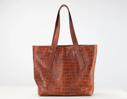 A brown crocodile-embossed leather tote bag with two shoulder straps, shown against a plain white studio background.