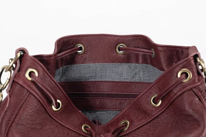Close-up of a maroon leather bag with gold accents on a white background