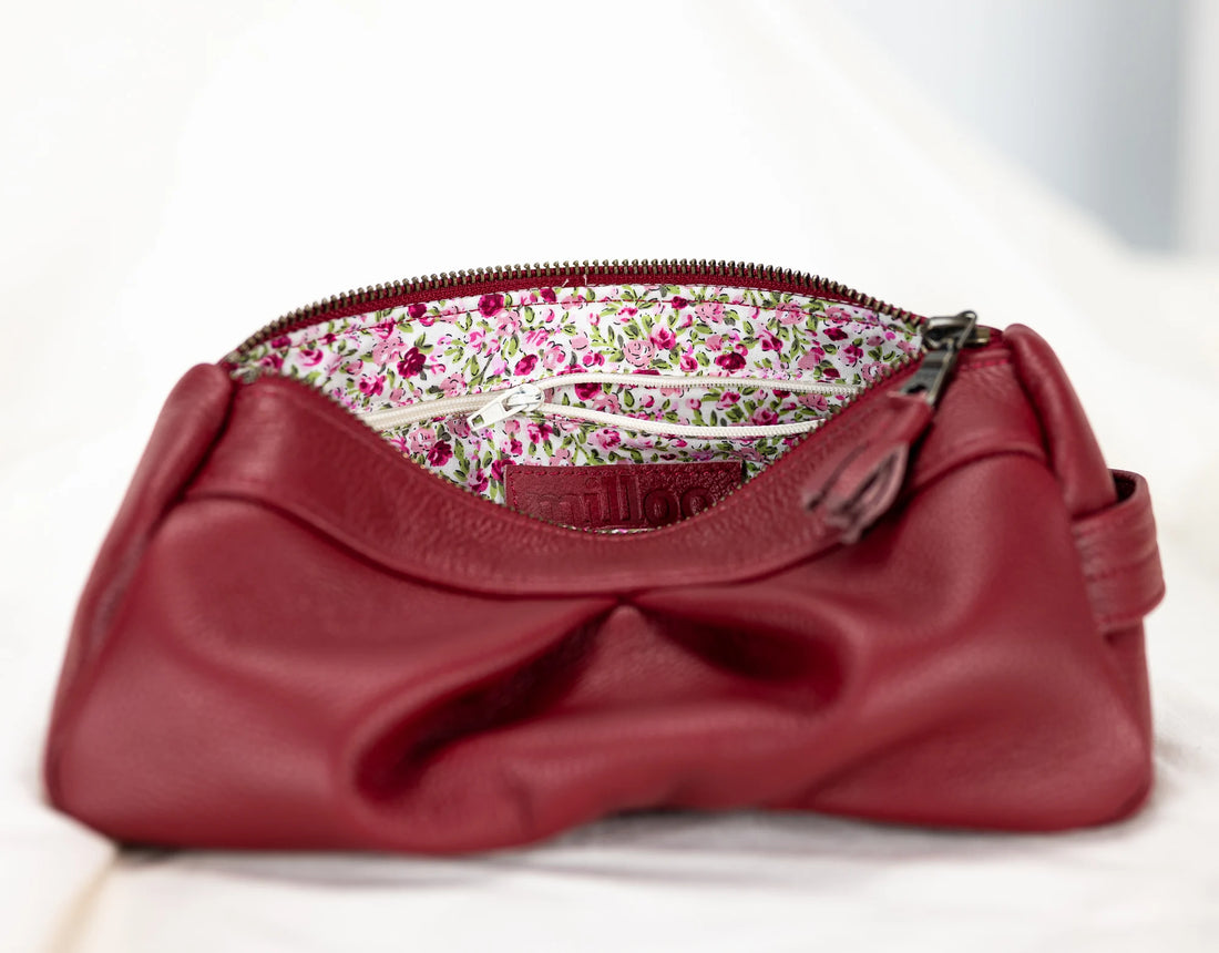 Red leather clutch bag with floral interior lining on a white background