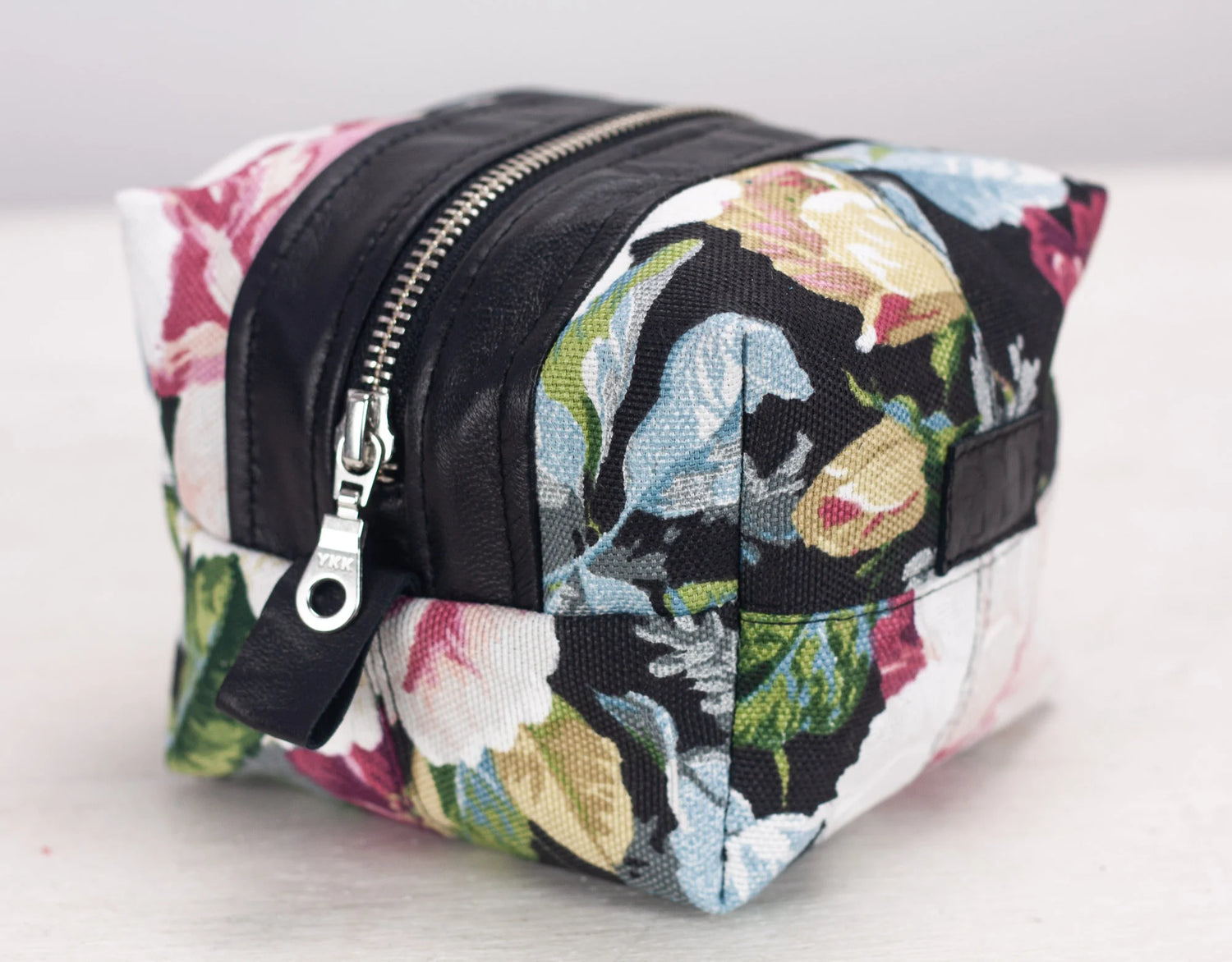 Floral patterned toiletry bag with black accents on a light background