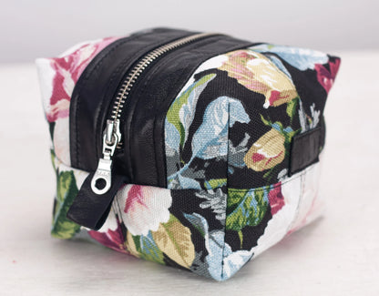 Floral patterned toiletry bag with black accents on a light background