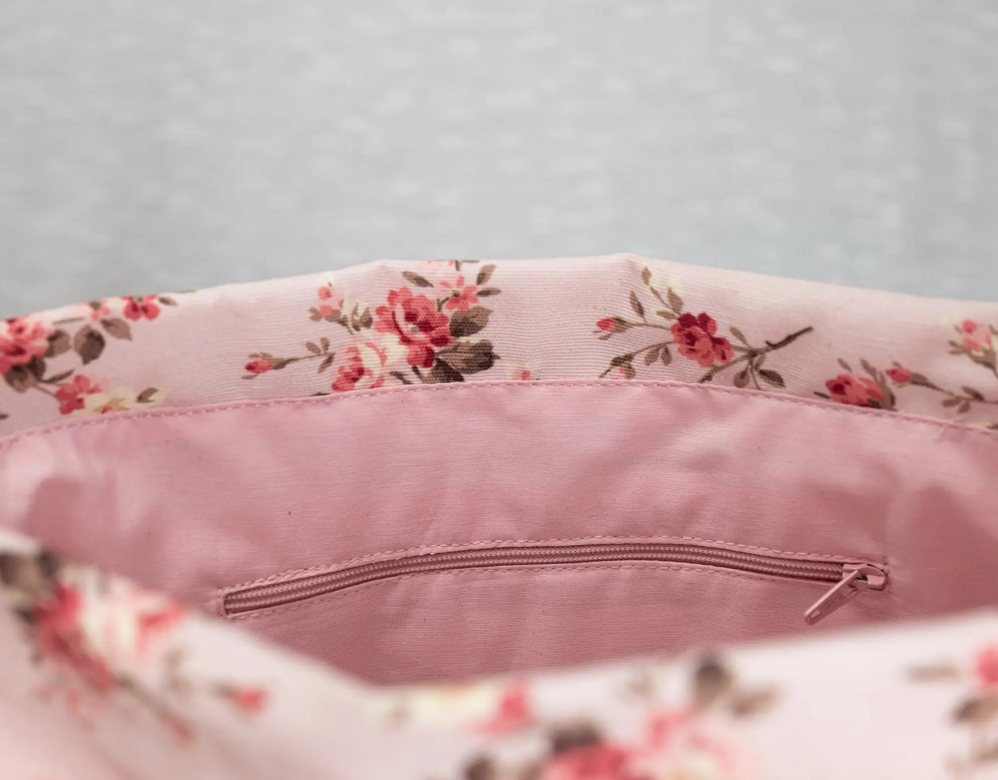 Floral-patterned cushion with a zipper on a light gray background