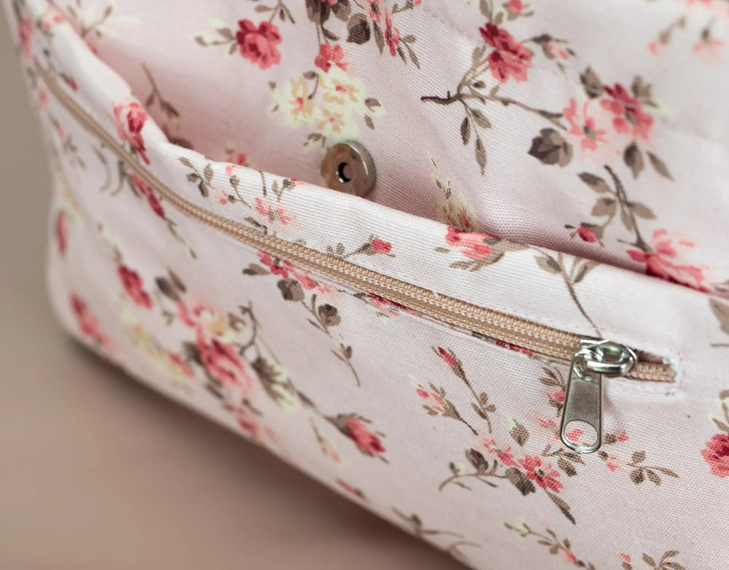Floral-patterned bag with a zipper on a neutral background