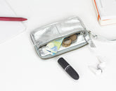 Silver wallet with coins, cards, and a lipstick on a white surface