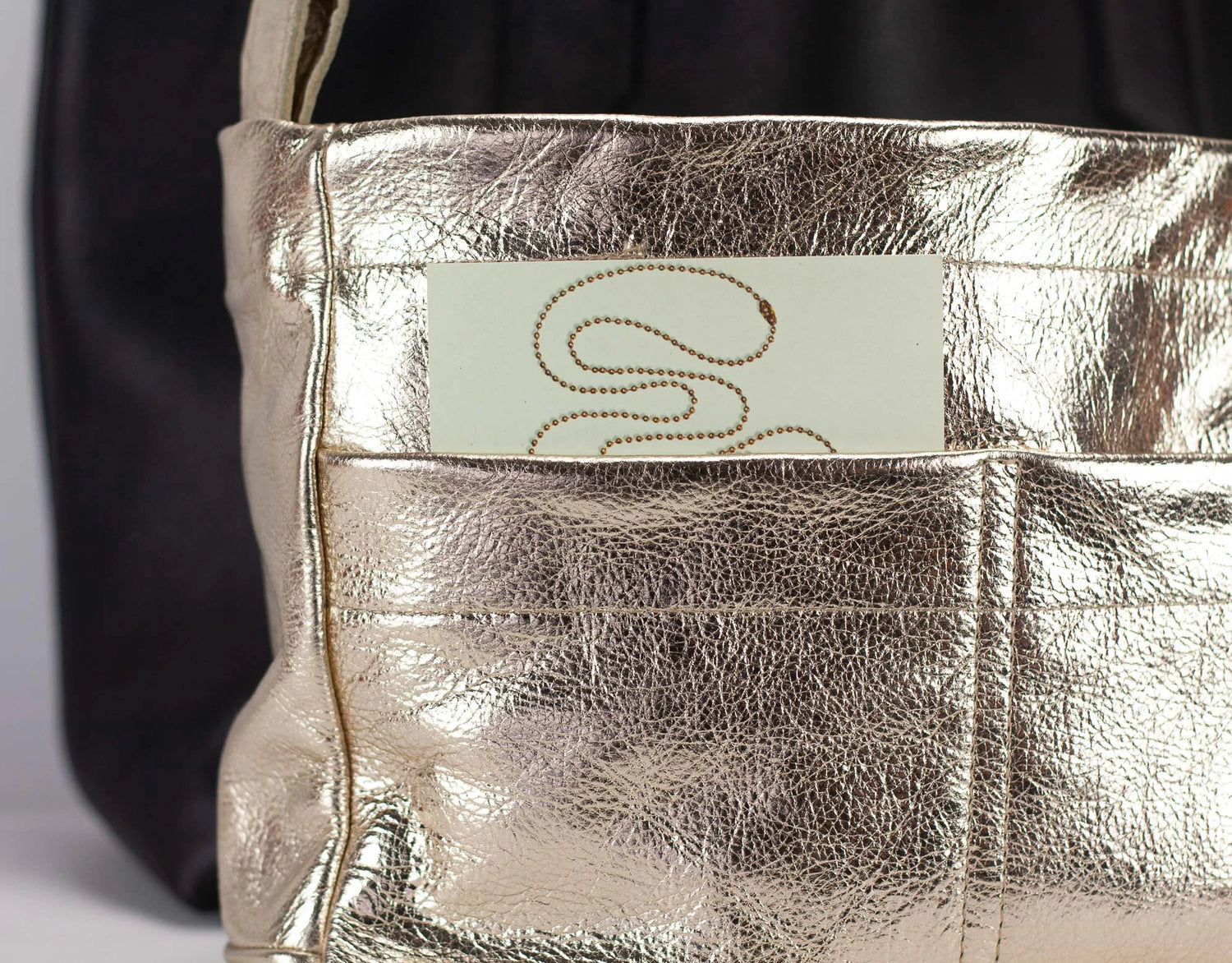 Metallic handbag with a visible brand name tag on a neutral background