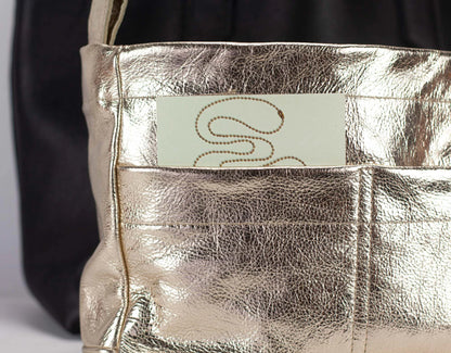 Metallic handbag with a visible brand name tag on a neutral background