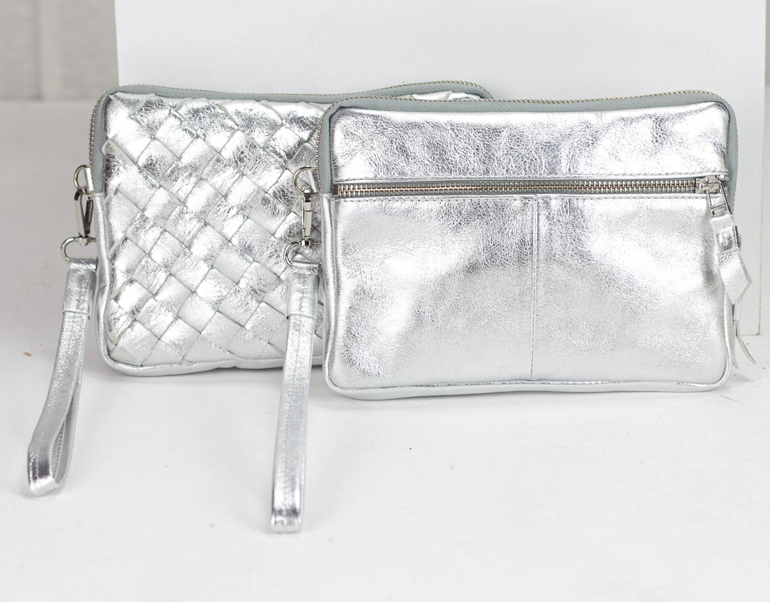 Two silver metallic handbags on a white background