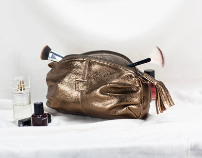 Brass makeup bag with cosmetic items on a white background
