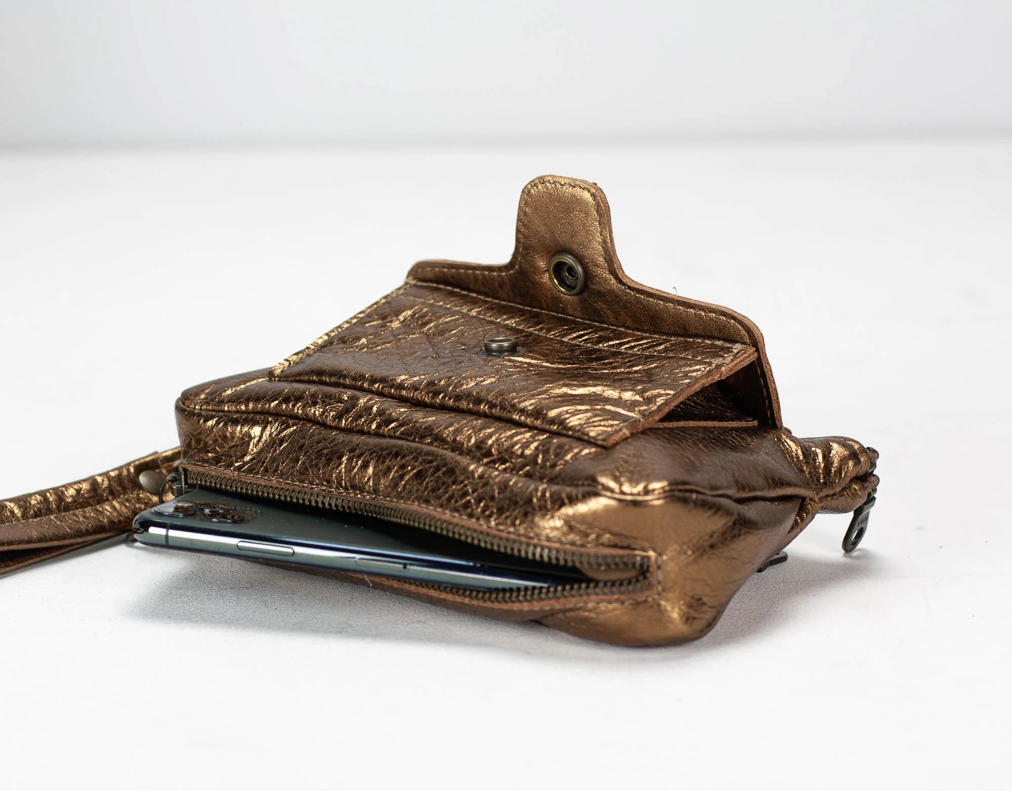 Brass leather crossbody bag with a phone case on a white background