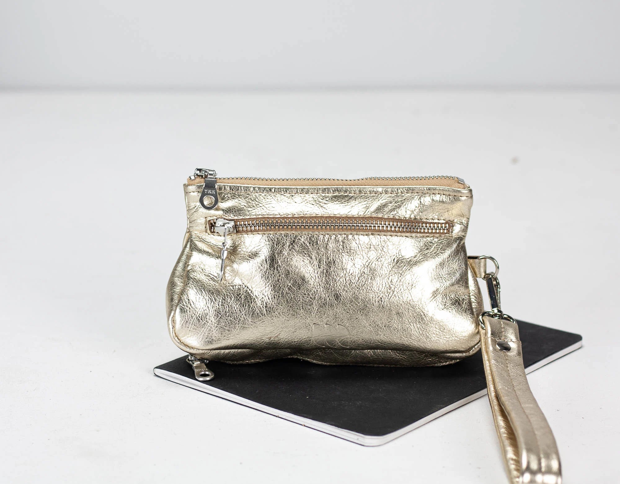 Gold metallic handbag with a strap on a white background