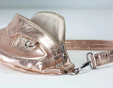 Rose gold handbag with a strap on a light gray background