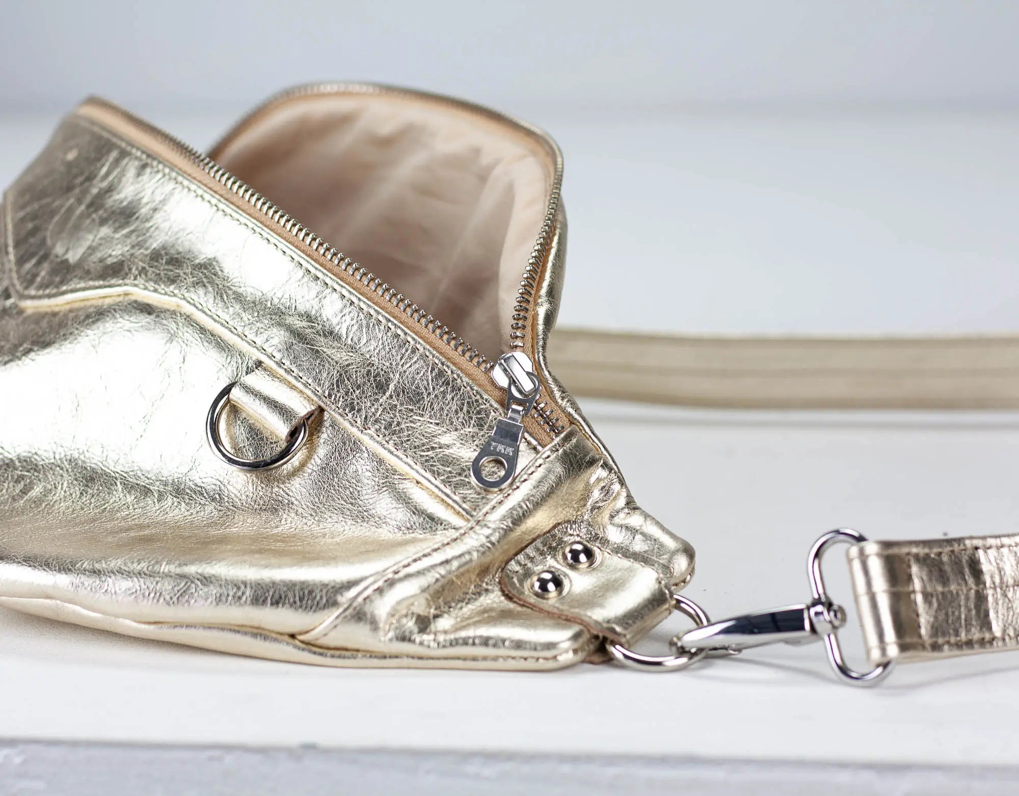 Gold metallic crossbody bag on a light gray background