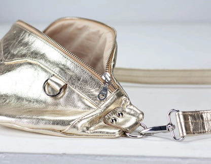 Gold metallic crossbody bag on a light gray background