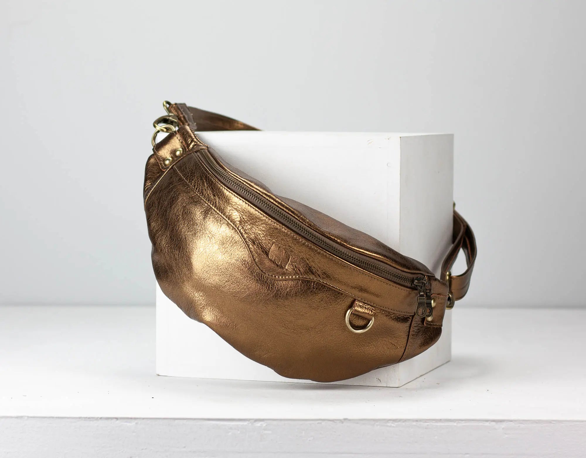 Gold leather bag on a white pedestal against a light gray background