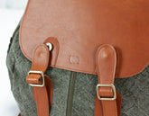 Close-up of a backpack with brown leather straps and a visible brand logo.