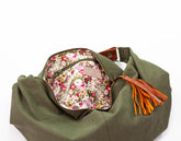 Green bag with floral pocket and orange tassel on a white background