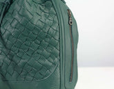 Green woven leather bag with a zipper on a light gray background
