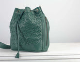 Green woven leather bag on a white surface with a light gray background
