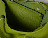 Close-up of the interior of a bright green pebbled leather bag, showing a zippered pocket and metal zipper hardware.