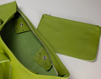 A close-up of a bright lime green pebbled leather bag showing the interior and a matching zippered pouch.
