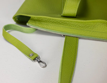 Close-up of a bright lime green pebbled leather bag with a matching wristlet strap and silver-tone metal clasp, shown on a white surface.