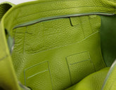 Close-up of the interior of a lime green pebbled leather bag, showing a zippered compartment and stitched pockets with the brand name &