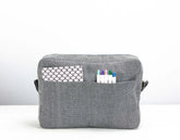Gray fabric pouch with a pocket and markers on a white background