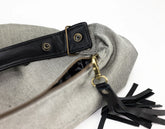 Gray bag with black strap and tassel on a white background