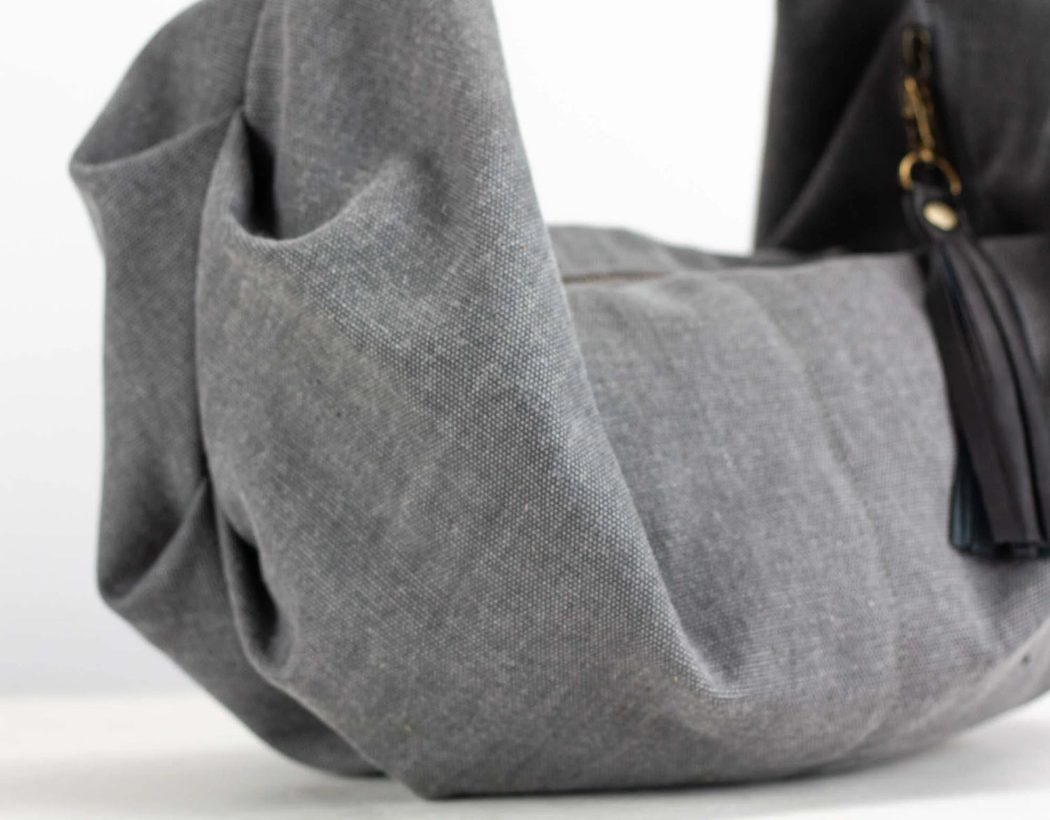 Gray handbag with a black strap on a white background