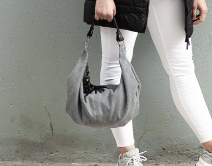 Person holding a gray handbag against a plain background