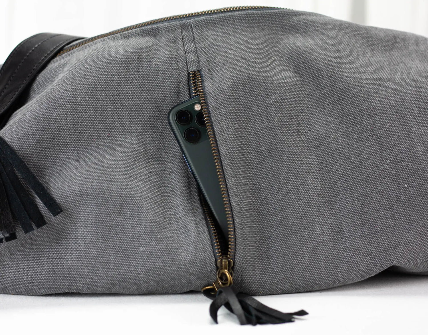 Gray duffel bag with black tassels on a white background