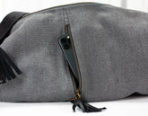 Gray duffel bag with black tassels on a white background