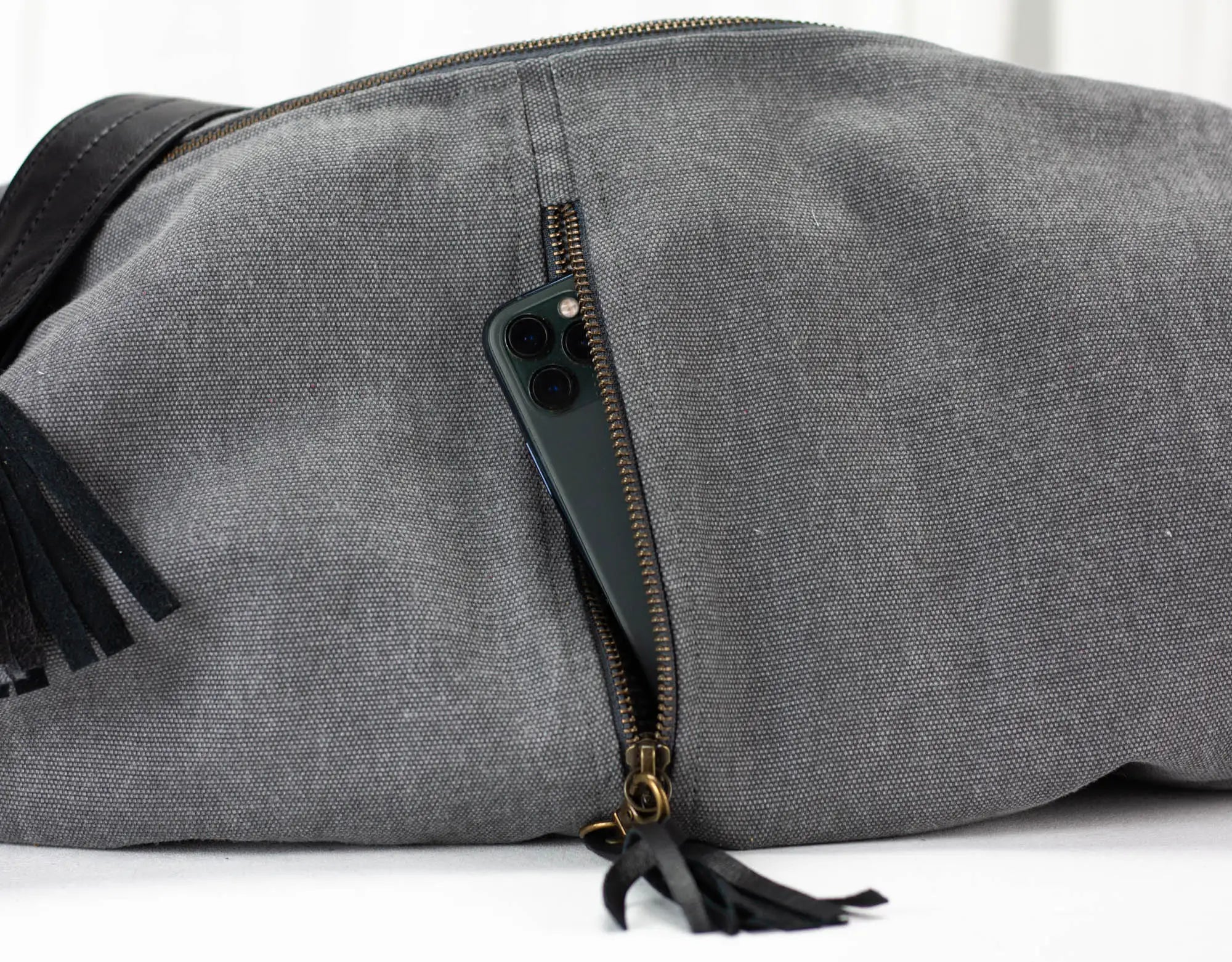 Gray duffel bag with black tassels on a white background