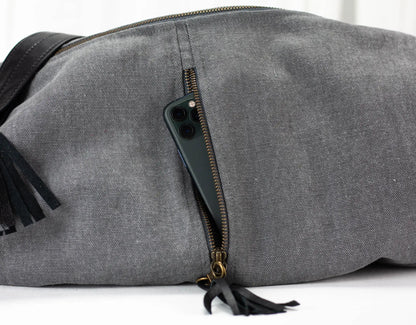 Gray duffel bag with black tassels on a white background