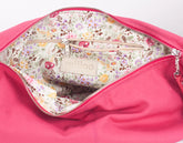 Pink bag with floral interior and visible brand logo on a white background